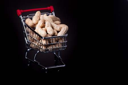 unshelled peanuts in the supermarket trolley on black backgroundの写真素材