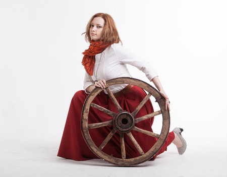 young woman with an old wagon wheel on white backgroundの写真素材