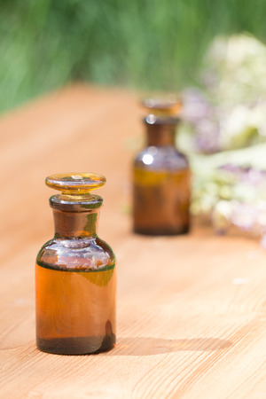 essential oil in little bottle and medical flowers herbs on wooden boardの写真素材