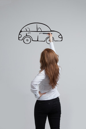 Young woman drawing car, concept on the subject of dreams or financial planningの写真素材