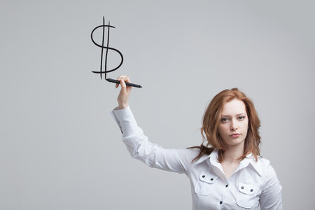 Young woman drawing dollar symbol on grey backgroundの写真素材