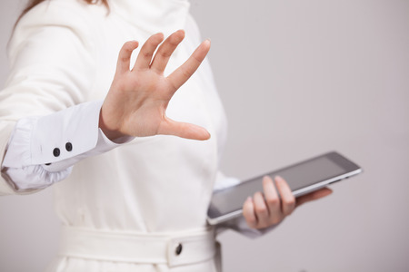 Young girl working with virtual screen on gray background