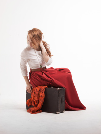 Young Woman sitting on a suitcase, isolated on white backgroundの写真素材