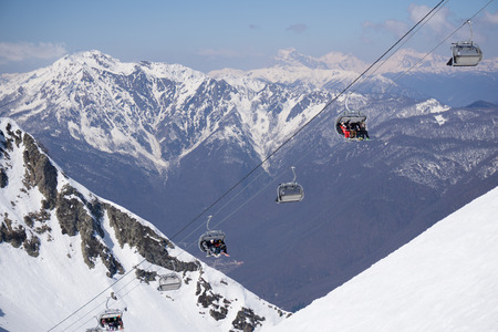 Skiers and snowboarders on a mountain ski liftの写真素材