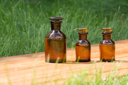 little brown bottles on booden board and green grassの写真素材