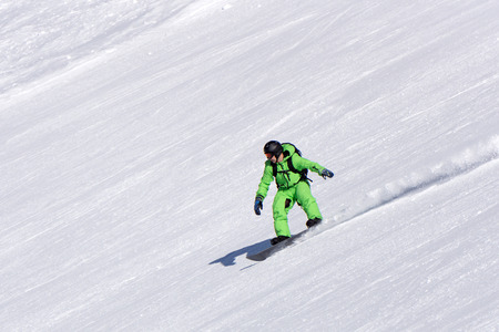 Snowboarder going down the slope at ski resort, extreme winter sportの写真素材