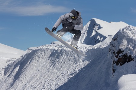 Flying snowboarder on mountains. Extreme winter sport.の写真素材