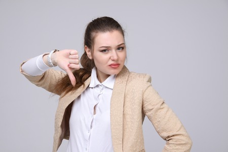 Business woman in beige jacket showing thumb down