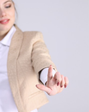 woman presses a virtual button, on grey backgroundの写真素材