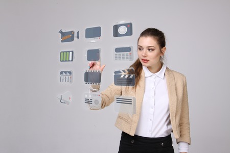 Young businesswoman pressing high tech type of modern multimedia buttons on a virtual backgroundの写真素材