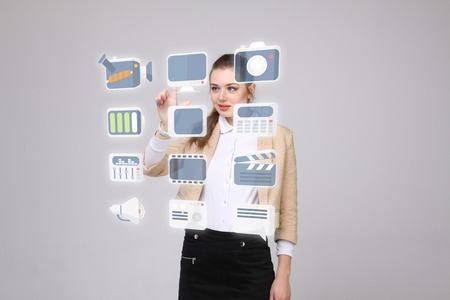 Young businesswoman pressing high tech type of modern multimedia buttons on a virtual backgroundの写真素材