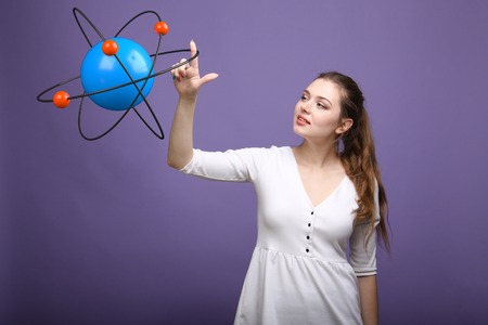 Woman scientist with atom model on violet background, research conceptの写真素材