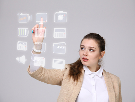 Young businesswoman pressing high tech type of modern multimedia buttons on a virtual backgroundの写真素材