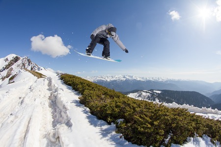 Snowboard jump on mountains. Extreme winter sport.の写真素材