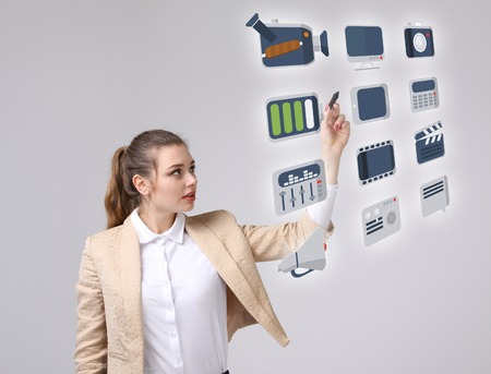 Young businesswoman pressing high tech type of modern multimedia buttons on a virtual background