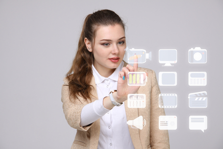 Young businesswoman pressing high tech type of modern multimedia buttons on a virtual backgroundの写真素材