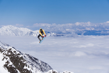 Snowboard rider jumping on snowy mountains. Extreme snowboard freeride sport.の写真素材