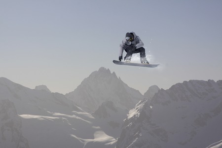 Snowboard rider jumping on snowy mountains. Extreme snowboard freeride sport.の写真素材