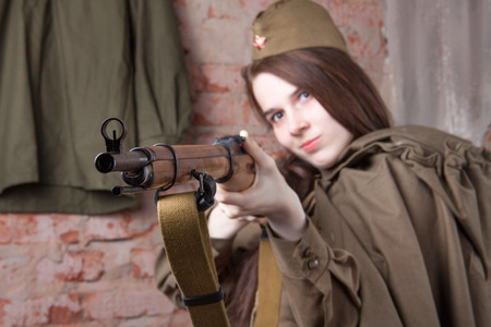 Young woman in Russian military uniform shoots a rifle. Female soldier during the second world war.の写真素材