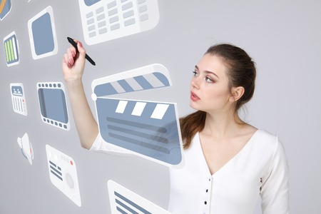 Young businesswoman pressing high tech type of modern multimedia buttons on a virtual backgroundの写真素材