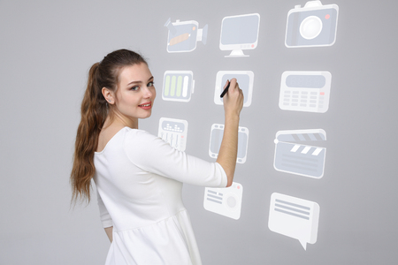 Young businesswoman pressing high tech type of modern multimedia buttons on a virtual backgroundの写真素材