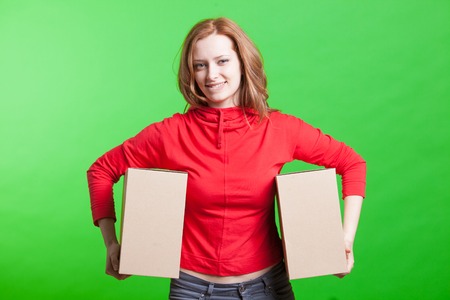 Young woman holding cardboard boxes on green backgroundの写真素材