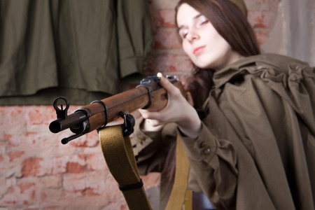 Young woman in Russian military uniform shoots a rifle. Female soldier during the second world war.の写真素材