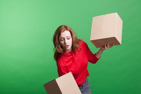 Young woman holding cardboard boxes on green background