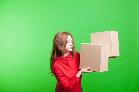 Young woman holding cardboard boxes on green backgroundの写真素材