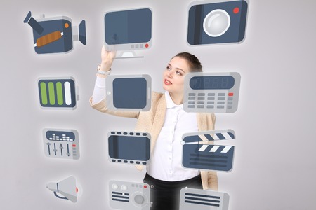 Young businesswoman pressing high tech type of modern multimedia buttons on a virtual backgroundの写真素材