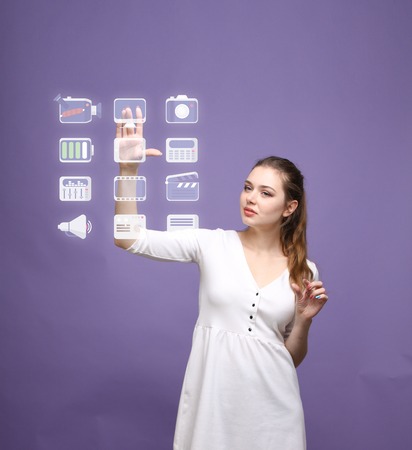Young woman pressing multimedia and entertainment icons on a virtual backgroundの写真素材