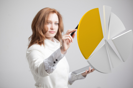 Young Businesswoman shows a pie chart (circle diagram) on grey background. Business analytics concept.の写真素材