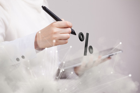 Woman showing symbol of percent. Bank Deposit or Sale concept on grey background.の写真素材