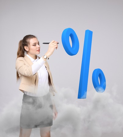 Woman showing symbol of percent. Bank Deposit or Sale concept on grey background.の写真素材