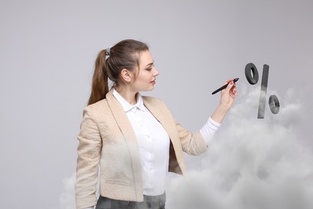 Woman showing symbol of percent. Bank Deposit or Sale concept on grey background.の写真素材