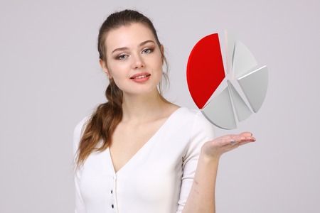 Young Businesswoman shows a pie chart (circle diagram) on grey background. Business analytics...