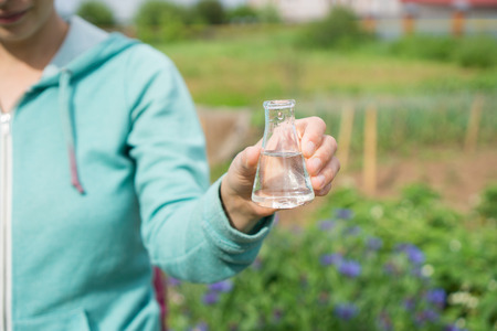 Female hand with a test tube and plant. Fertilizer in laboratory glassware.の写真素材