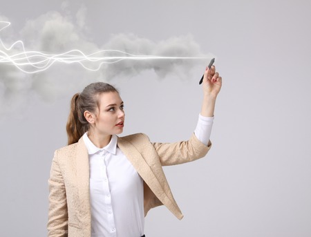 Young woman with pen or stylus making magic effect - flash lightning. The concept of copywriting or writing.の写真素材