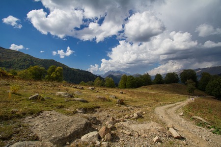 Summer mountain landscape with cumulus cloud on blue sky.