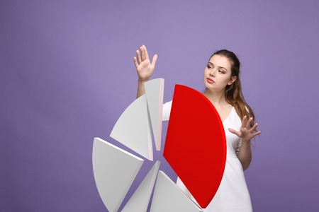 Young Businesswoman shows a pie chart (circle diagram) on violet background. Business analytics concept.の写真素材