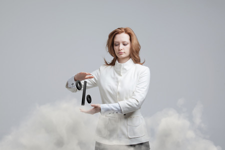 Woman showing symbol of percent. Bank Deposit or Sale concept on grey background.の写真素材