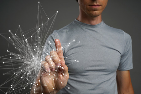 Young man in t-shirt working with linked dots on grey background. Wireless connection or global network concept.の写真素材