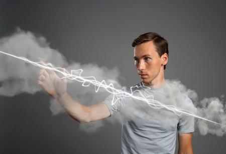 Young man making magic effect - flash lightning. The concept of electricity, high energy.の写真素材