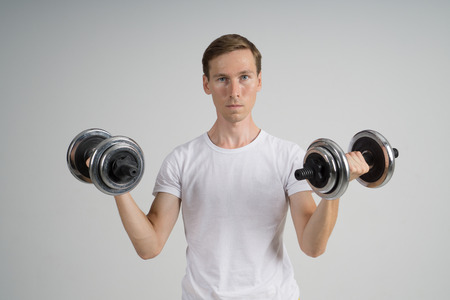 Young Man in white Sports Wear doing Exercise with Dumbbells.の写真素材