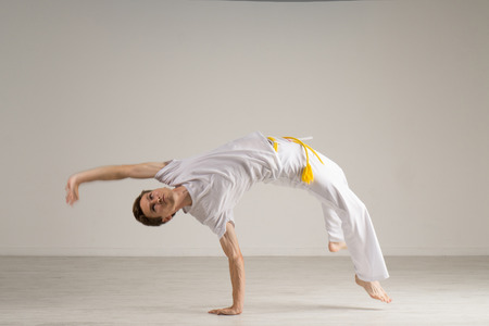Young Man practicing Capoeira (brazilian martial Art with Elements of Dance, Acrobatics and Music).の写真素材