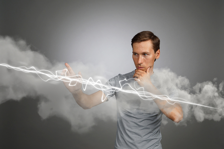 Young man making magic effect - flash lightning. The concept of electricity, high energy.