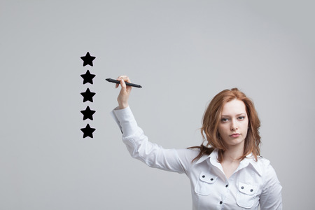 5 star rating or ranking, benchmarking concept on grey background. Woman assesses service, hotel or restaurantの写真素材