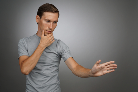 Young man in t-shirt working with transparent virtual interface screen.の写真素材