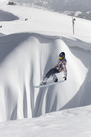 Snowboarder flying on the background of snowy slope. Extreme winter sports, snowboarding.の写真素材