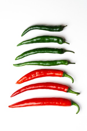 Green and red chili peppers on white background top view. Hot spicy food.の写真素材